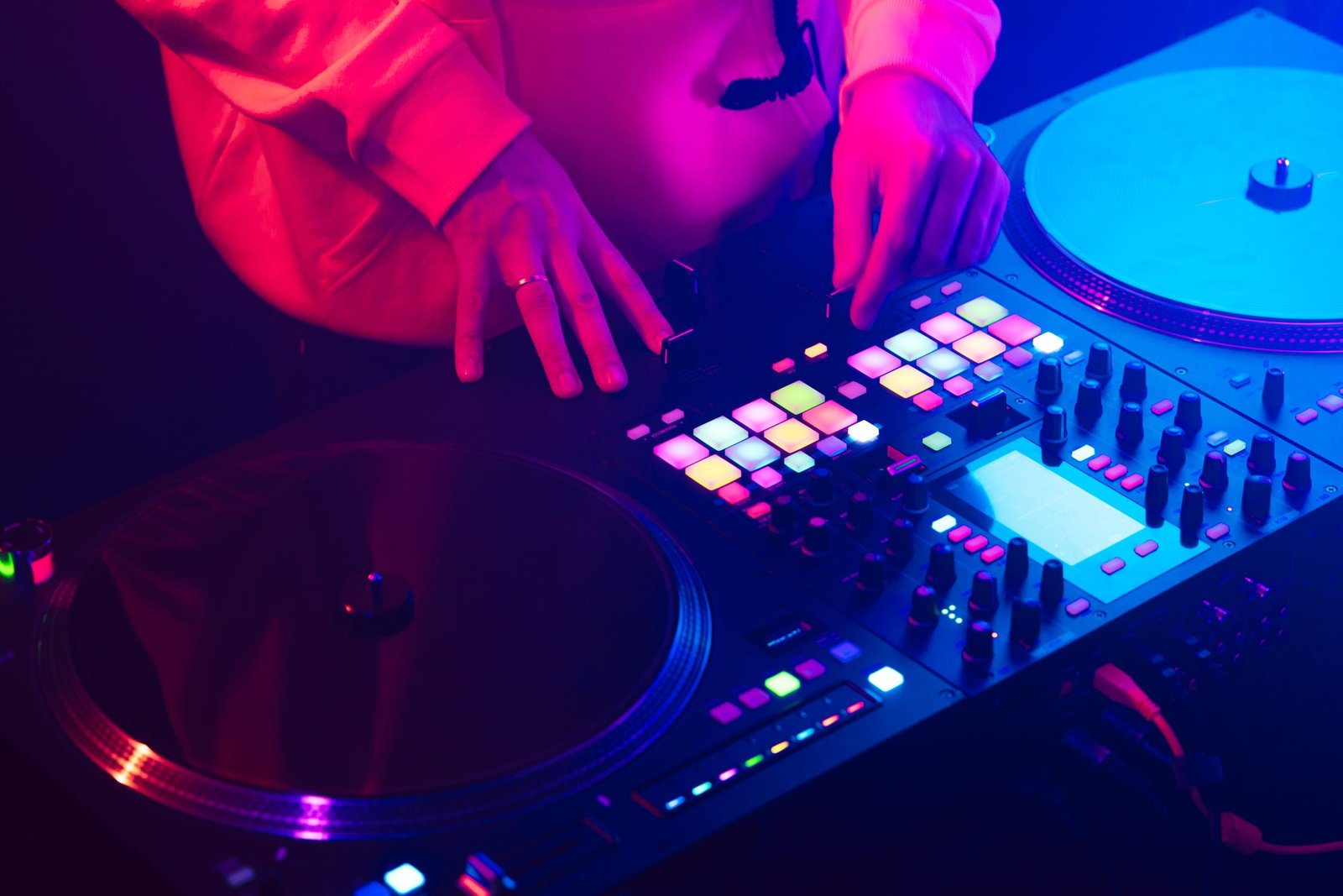 Hands of a DJ creating and regulating music on dj console mixer at club concert